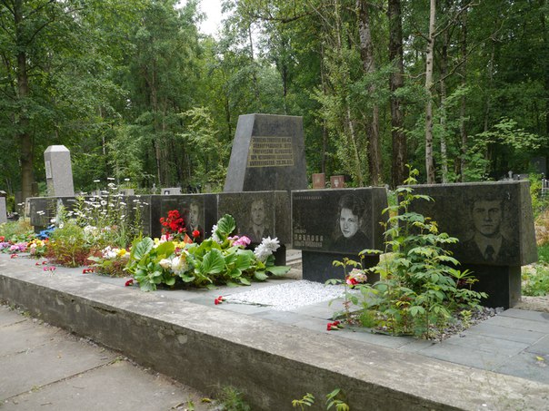 Могила з квітами на кладовищі серед лісу.