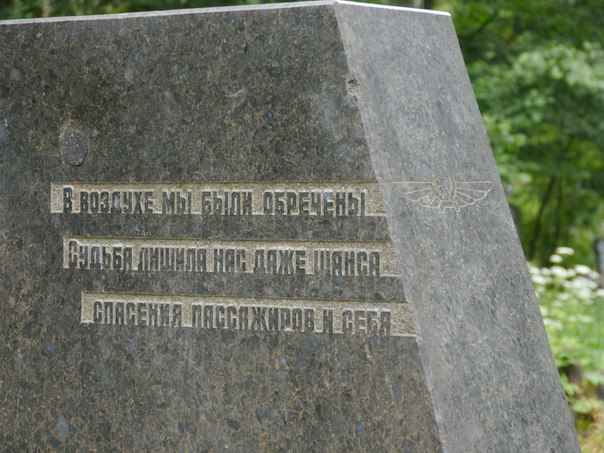 Пам'ятник з написами про трагедію, пов'язану з авіацією, серед зелені.