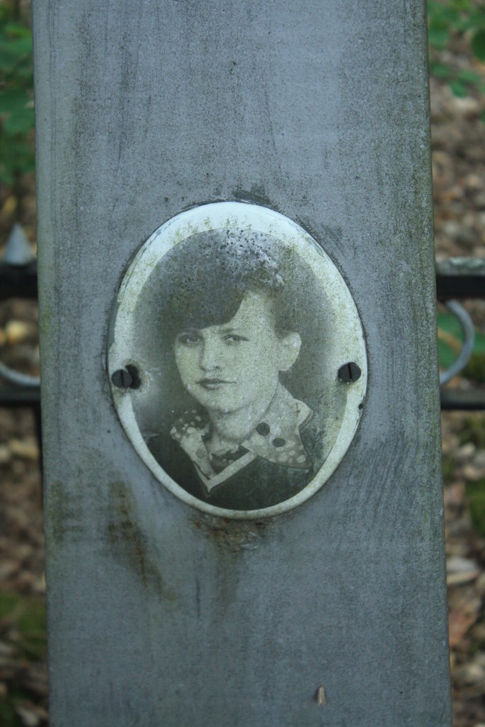 Портрет молодої людини на пам'ятнику, забруднений і зношений, прикріплений до вертикальної поверхні.