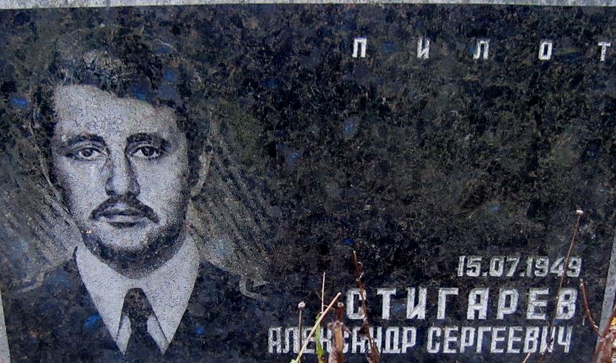 Меморіальна плитка з зображенням чоловіка в військовій формі, ймовірно, пілота, на фоні темного граніту з написом його імені та датою народження.
