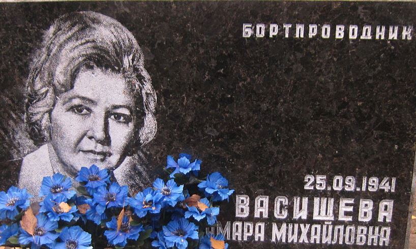 Кам'яна плита з портретом жінки та написом з її ім'ям, датою народження і квітами на пам'ятнику.